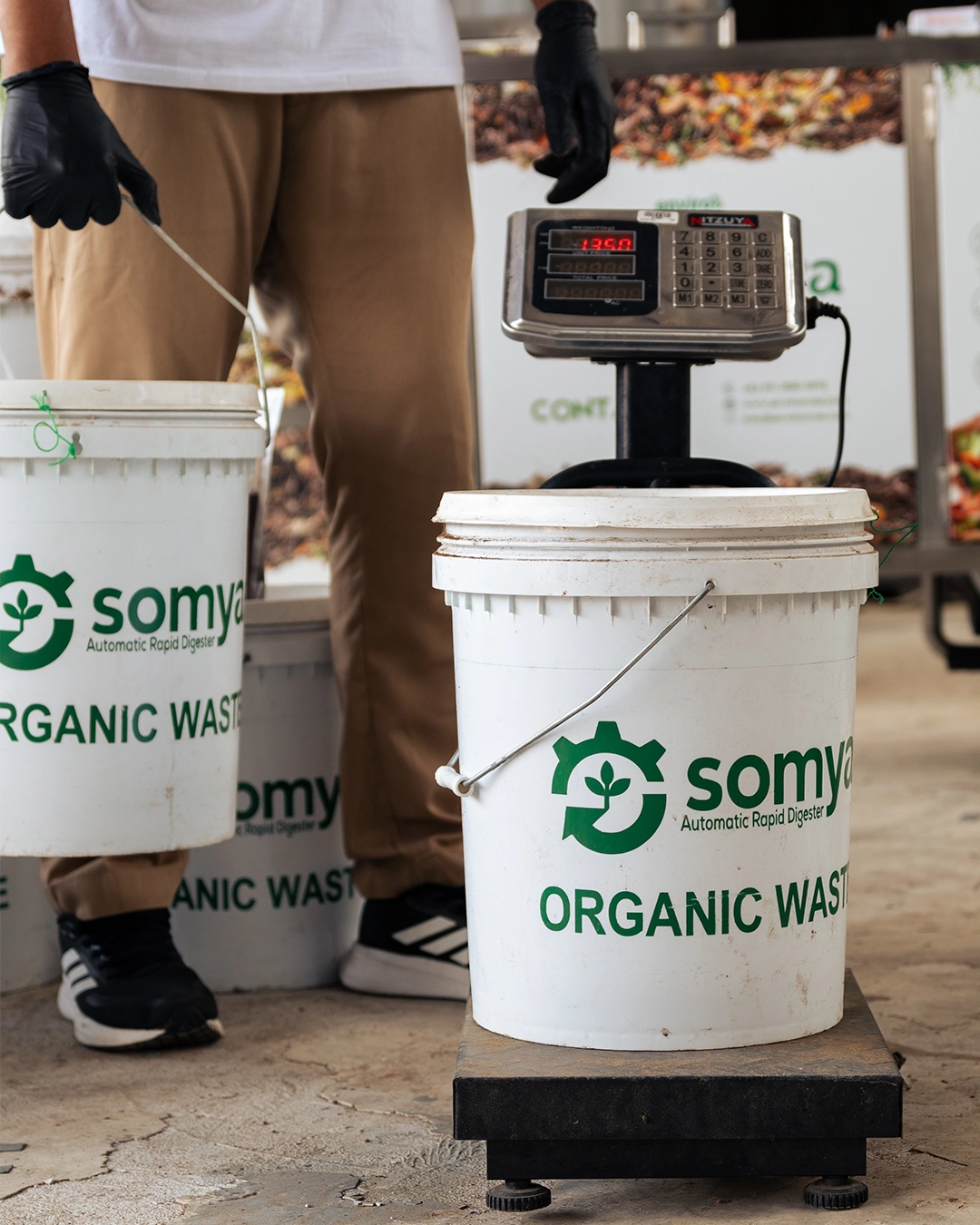 Petugas menimbang ember SOMYA Organic Waste di atas timbangan untuk pencatatan per klien
