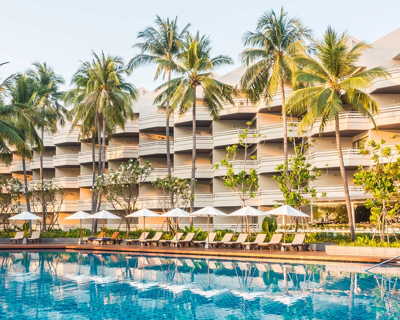 Hotel resor tepi kolam renang dengan pohon kelapa di Bali